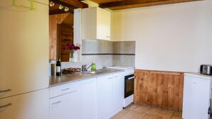 A compact kitchen with white cabinets, a wooden ceiling, and a tiled backsplash. - Baita Ficc by Interhome (Ponto Valentino)