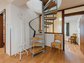 A modern interior with a spiral staircase, wooden flooring, and a white chair. - Vacation home Riki by Interhome (Bruck)