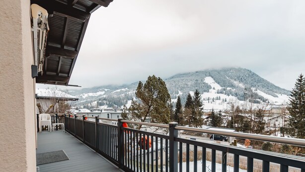 Un balcon avec vue sur des montagnes enneigées et une route.
