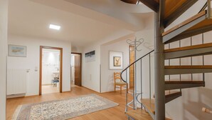 Une pièce spacieuse avec un plancher en bois, un escalier en colimaçon et un grand tapis.