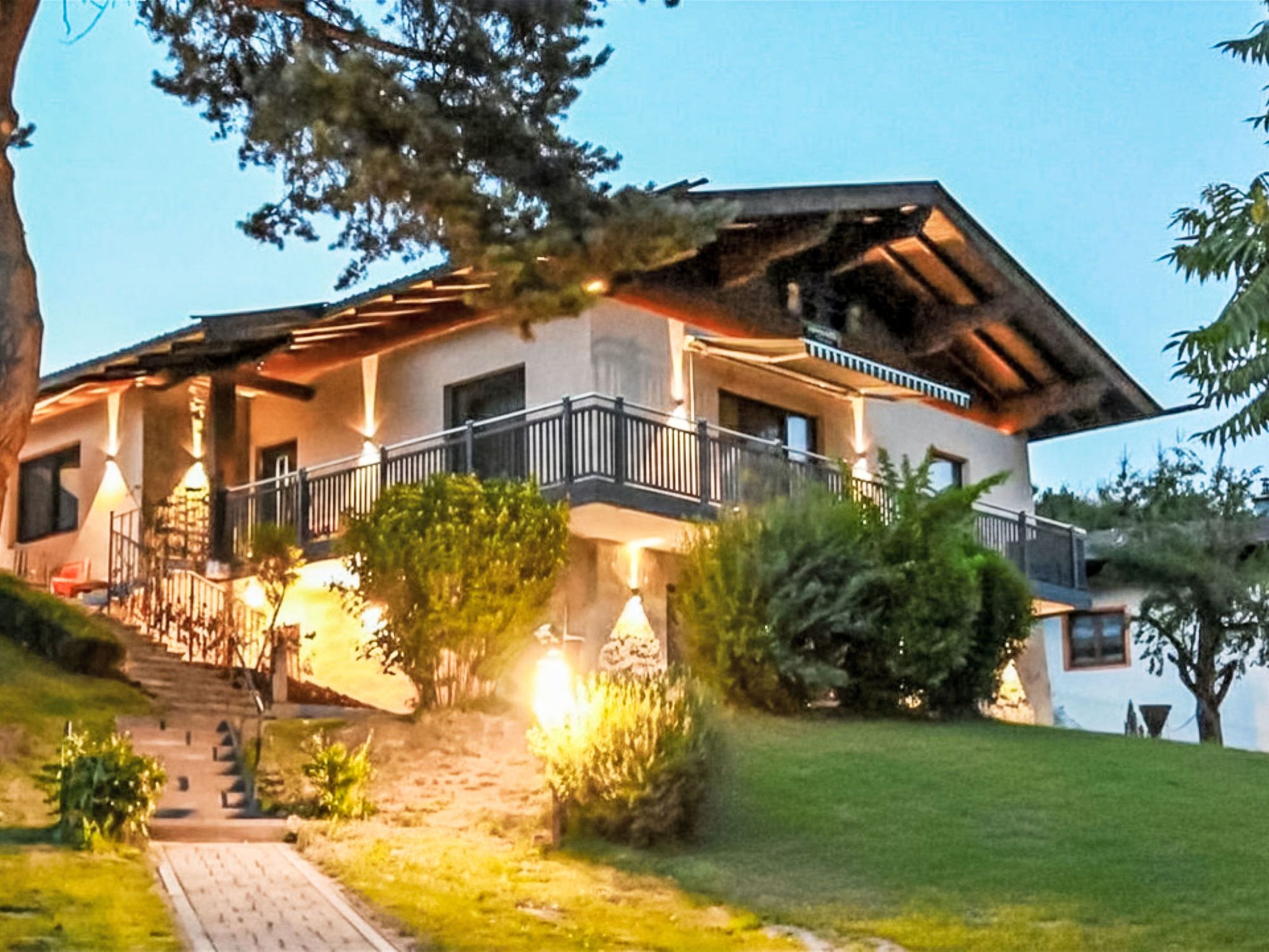 A multi-story building with a balcony, a stone staircase, and a well-maintained lawn.