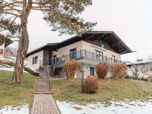 Un edificio a due piani con un balcone e una scalinata che conduce all'ingresso, su un terreno innevato.