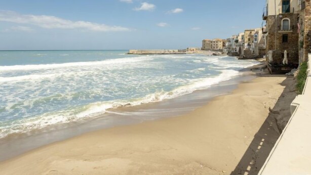 A beach with a stone building on the right and a clear sky. - Jancaliva by Interhome (Cefalù)