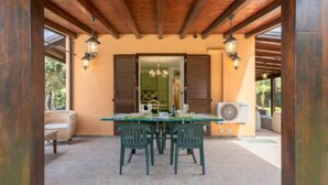 An outdoor patio with a table and chairs, wooden beams, and a view into a building. - Jancaliva by Interhome (Cefalù)
