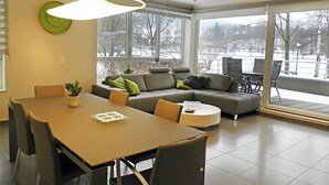 Un salon moderne avec une table à manger, un canapé et de grandes fenêtres.