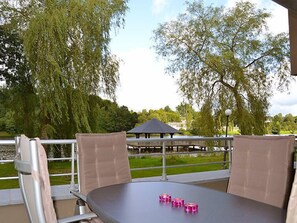 Un espace extérieur aménagé avec une table et des chaises, un gazebo en arrière-plan et des arbres tout autour.