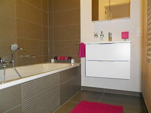 Une salle de bain moderne avec une baignoire, un lavabo et un miroir.