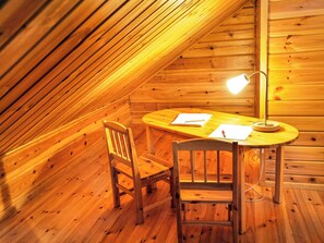 Een houten interieur met een schuine kap, een tafel met papieren en een pen, en twee stoelen.