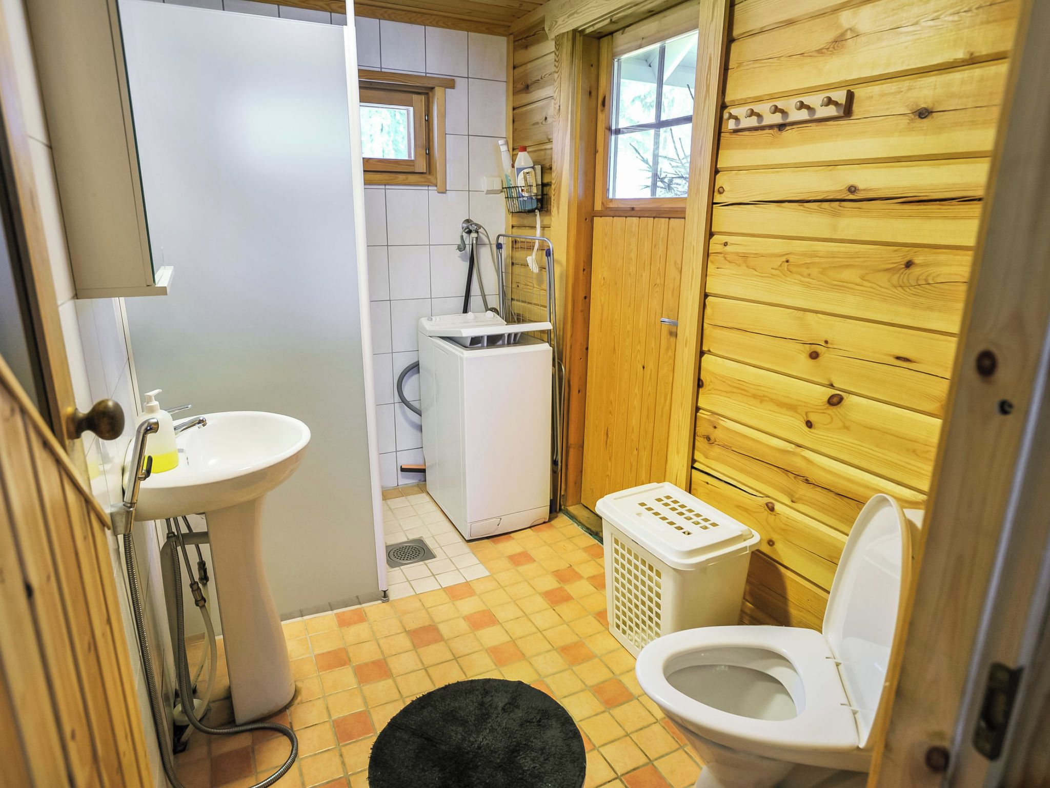 Ett litet badrum med handfat, toalett och tvättmaskin.