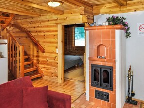 L'intérieur d'un chalet en bois, avec une cheminée, un lit et un canapé rouge.