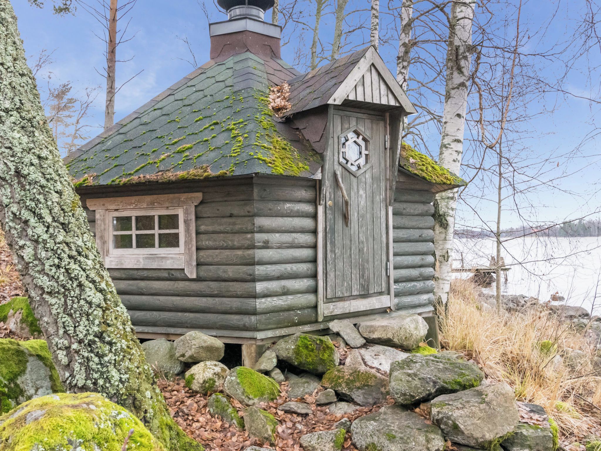 En rustik hytte med skorsten, et vindue og en dør.