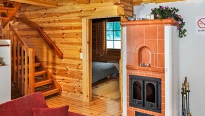 Un interno di una baita in legno con camino, una scala e un letto.