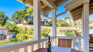 Ein Balkon mit einem Tisch für zwei Personen, mit Blick auf eine Wohngegend mit Häusern und Grünflächen.