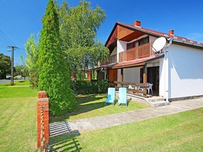 Une maison à deux étages avec un balcon, une antenne parabolique et une allée pavée.