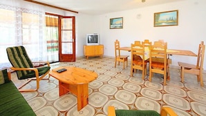 Una sala de estar acogedora con un sofá, una mesa de madera y un televisor sobre un mueble.