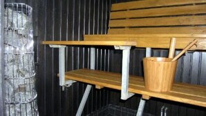 Uma sauna com um banco de madeira e um recipiente de metal.