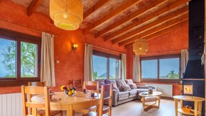 A cozy living room with a wooden dining table, chairs, a sofa, and a fireplace. - Cala Torta Na Moli by Interhome (Cala Torta)