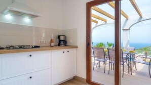 A modern kitchen with white cabinetry, a gas stove, and a coffee maker. - Cala Torta Na Moli by Interhome (Cala Torta)