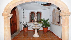 An arched corridor with tiled flooring, potted plants, and a central fountain. - Amadorio by Interhome (Jávea)