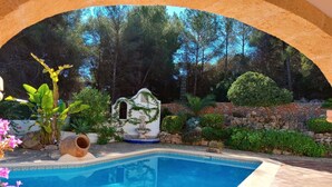 A swimming pool with a stone wall and greenery. - Amadorio by Interhome (Jávea)