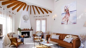 Un salón amplio con chimenea, un sofá grande, una mesa de centro y un cuadro en la pared.