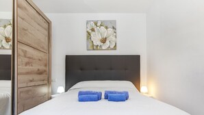 A hotel room with a bed, a wooden wardrobe, and a painting of flowers on the wall. - Mercury by Interhome (Lloret de Mar)
