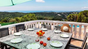 An outdoor dining area with a table set for four, surrounded by a white balustrade, overlooking a scenic landscape. - Mercury by Interhome (Lloret de Mar)