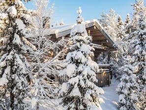 Une cabane en bois entourée d’arbres couverts de neige.