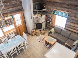 L’intérieur d’une cabane en rondins comprend une cheminée, un téléviseur, un coin repas et un canapé.
