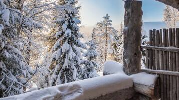 A wooden fence with snow accumulation, surrounded by snow-covered trees and a clear sky.