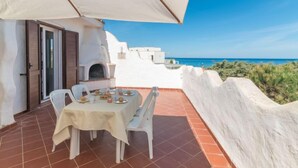 A terrace with a table set for dining, overlooking a coastal view. - Villa Selena by Interhome (Valledoria)