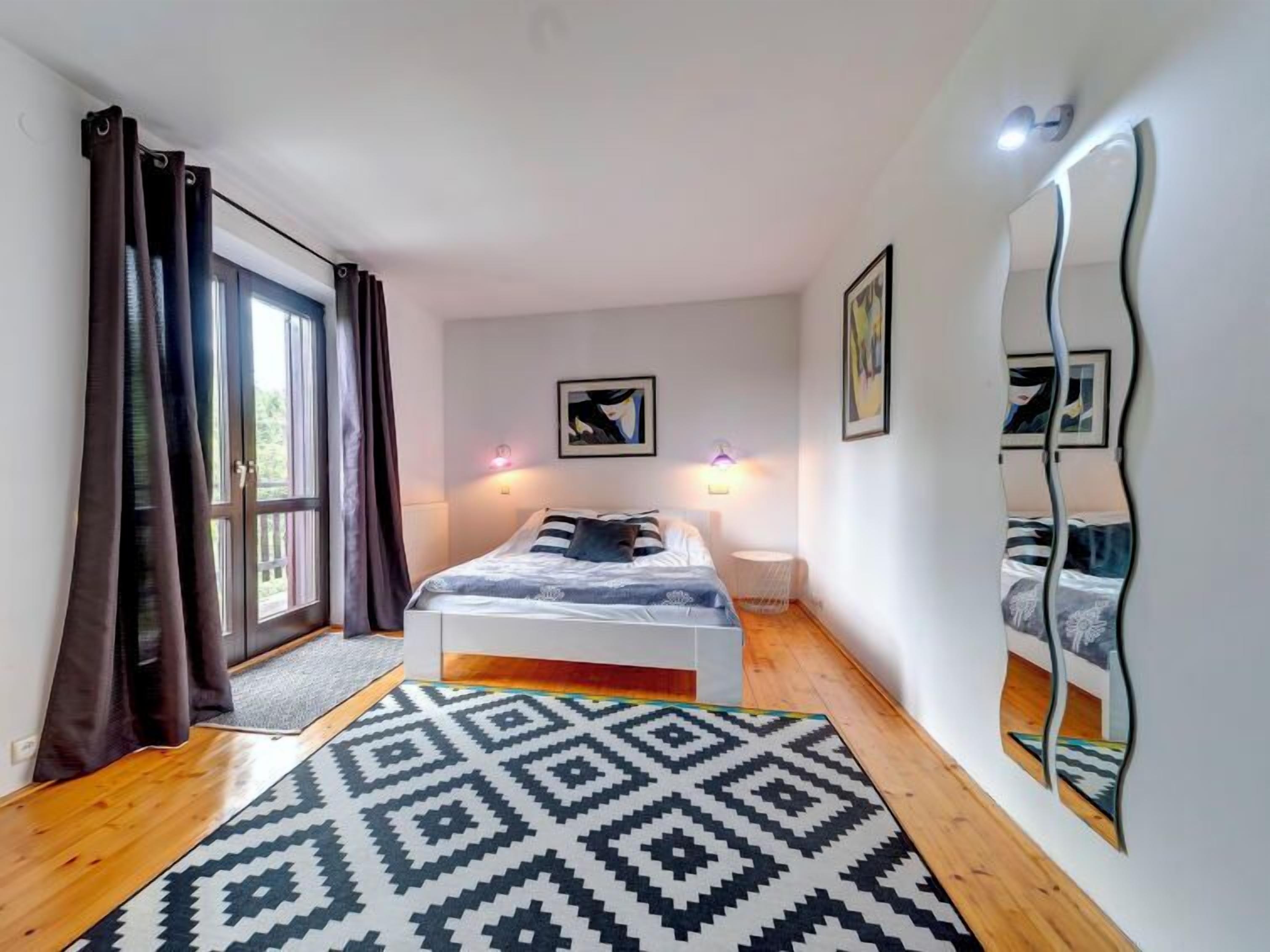 A bedroom with a bed, a mirror, and artwork on the walls.