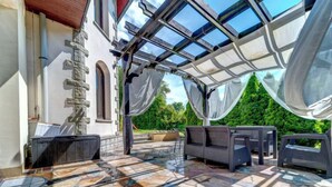 Un espace extérieur abrité, doté d’un sol en pierre, d’un canapé et d’une table.