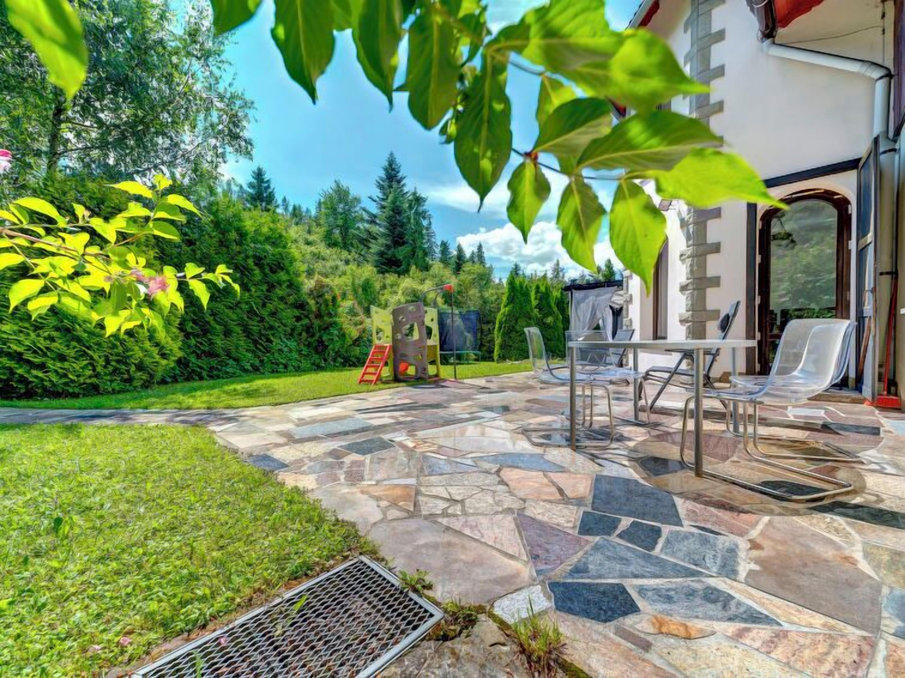 A patio with stone flooring, outdoor furniture, and a playground.