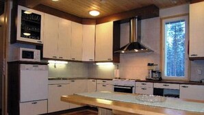 A modern kitchen with white cabinets, a wooden countertop, and a built-in oven.