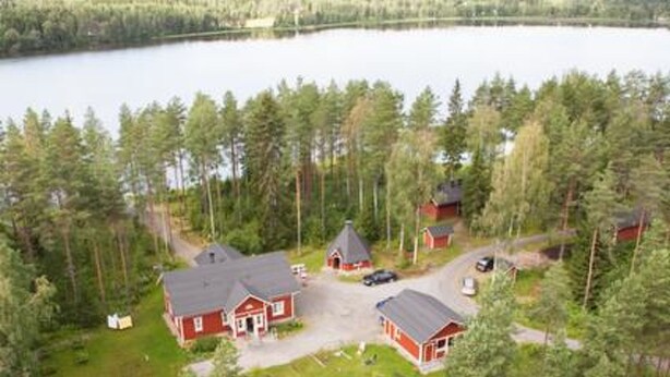 A cabin complex surrounded by dense forest and a lake.