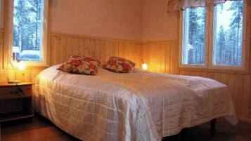 Ein Schlafzimmer mit einem Bett, zwei Nachttischen und zwei mit Vorhängen versehenen Fenstern.