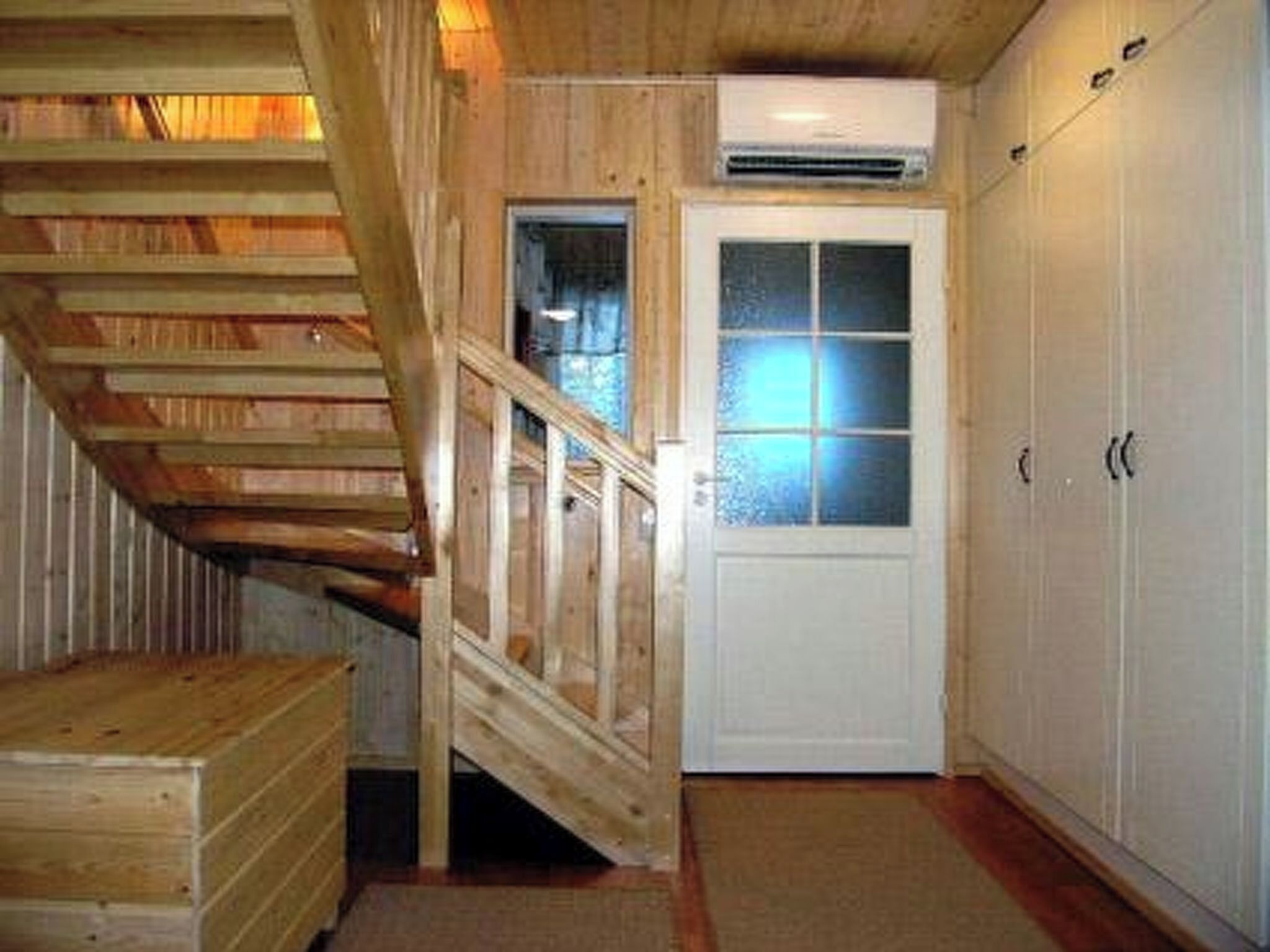 Uma escada de madeira leva a uma porta com painéis de vidro jateado.
