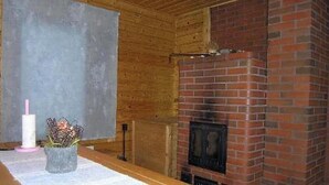 A room with a brick fireplace, wooden ceiling, and a concrete wall.
