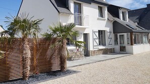 Een tweelaags huis met een schuin dak, witte buitenmuren en een balkon.