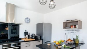 Een moderne keuken met een inbouwoven, een koffiezetapparaat en een eethoek met een tafel gedekt voor twee personen.