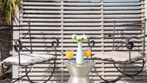 Een buitenzitgedeelte met metalen frame, twee comfortabele stoelen en een metalen tafel.
