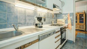 Una cocina moderna con gabinetes blancos, un lavamanos de acero inoxidable, una cafetera y una estufa.