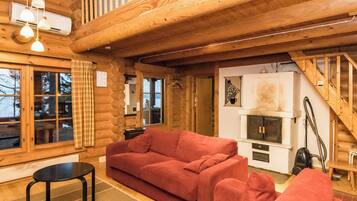 A log cabin interior with a red sofa, a small table, and a fireplace.