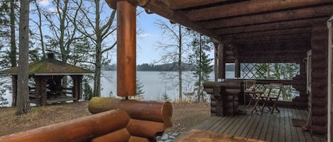 A wooden deck with a table and chairs, overlooking a lake.