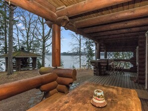 A wooden deck with a table and chairs, overlooking a lake.