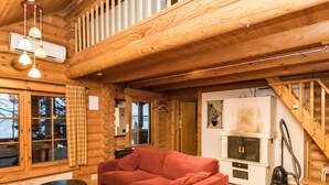 A cozy log cabin interior with a large red sofa, a small black table, and a fireplace.