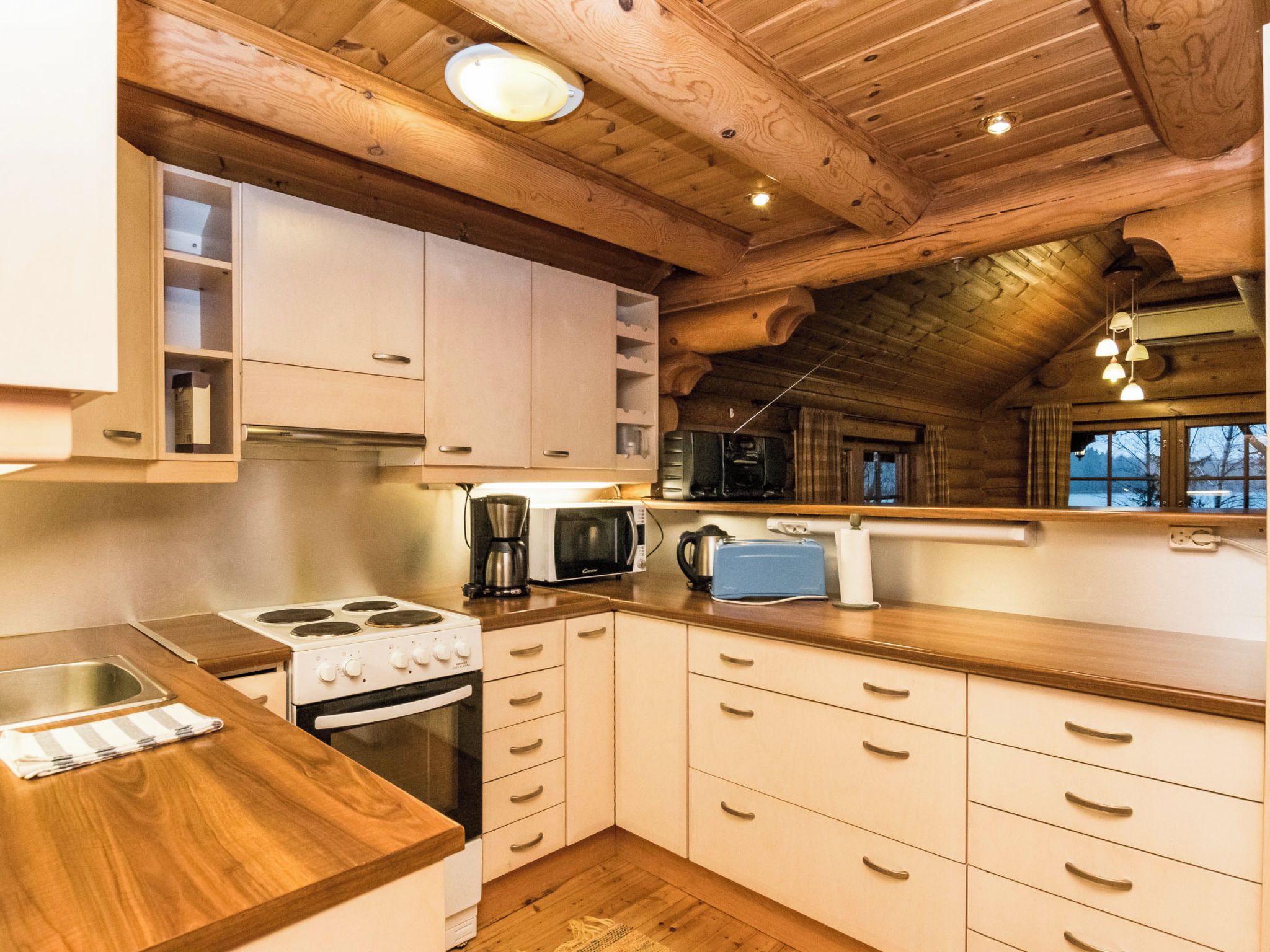 Une cuisine avec des meubles de rangement en bois, une cuisinière, un four à micro-ondes et un grille-pain.