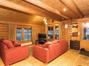 En stuga med träpanel, inredd med en soffgrupp, en tv och väggar av trä.