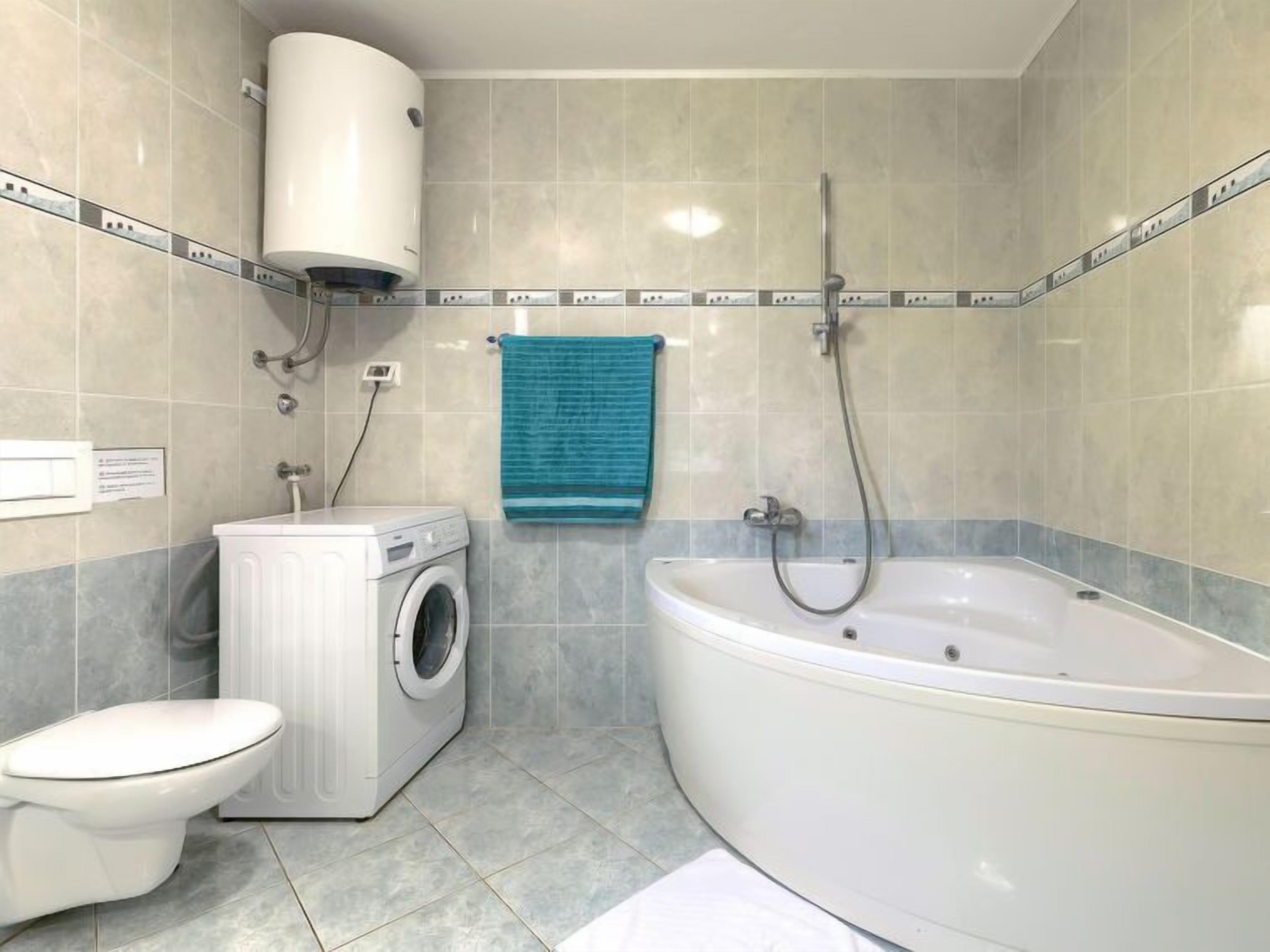 Ein Badezimmer mit Waschmaschine, Toilette und Badewanne.